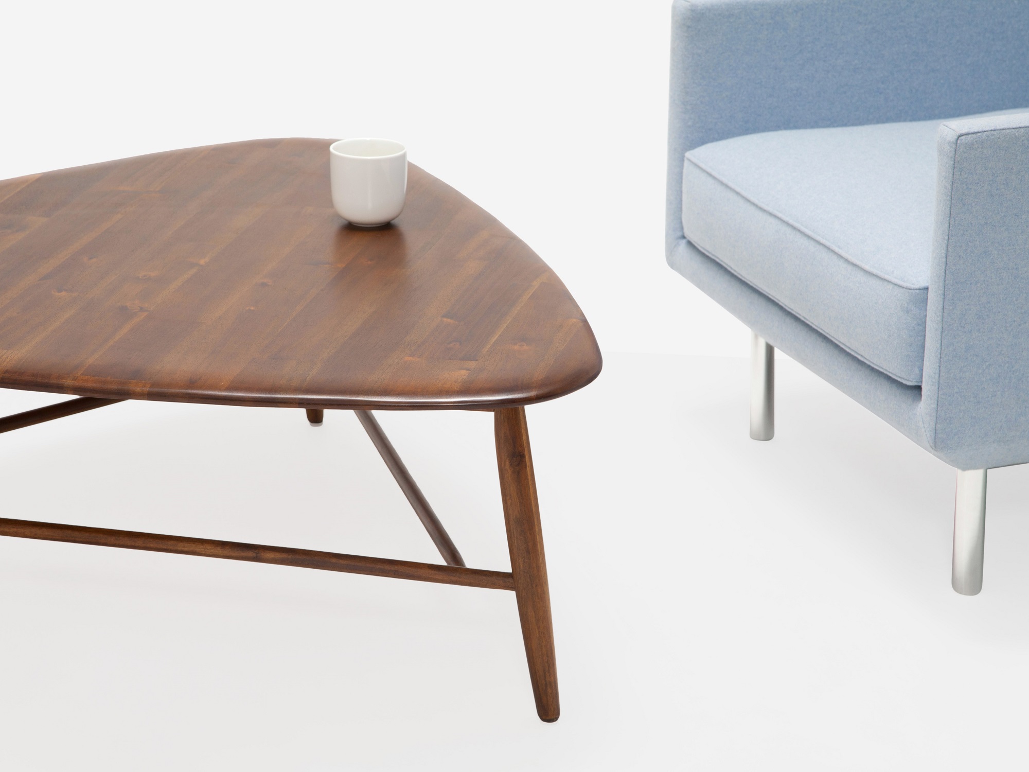 Detail view of java tri coffee table with blue chair and white mug